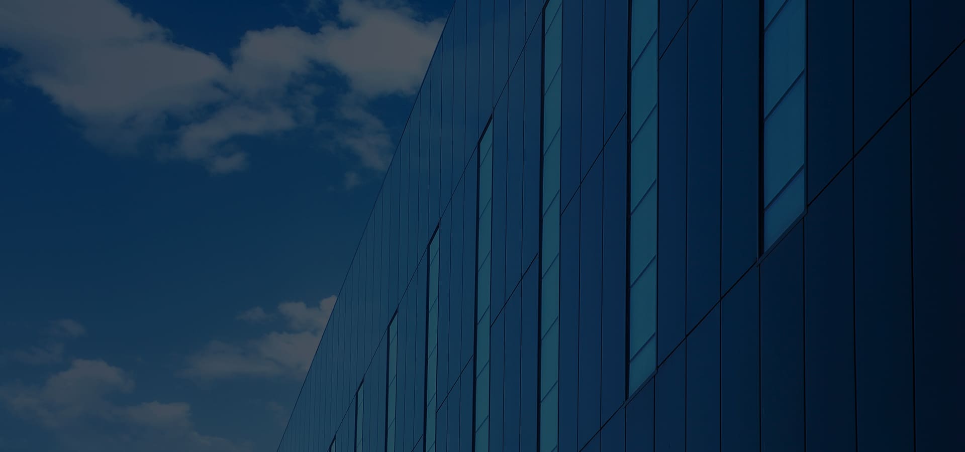 Deep blue metal panel wall facade seen from below against the sky
